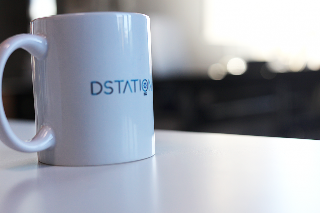 A mug sits on the desk, with the text DSTATION printed on it.